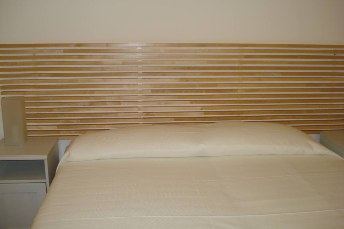 A bed with a wooden headboard, a bedside table, and a nightstand.