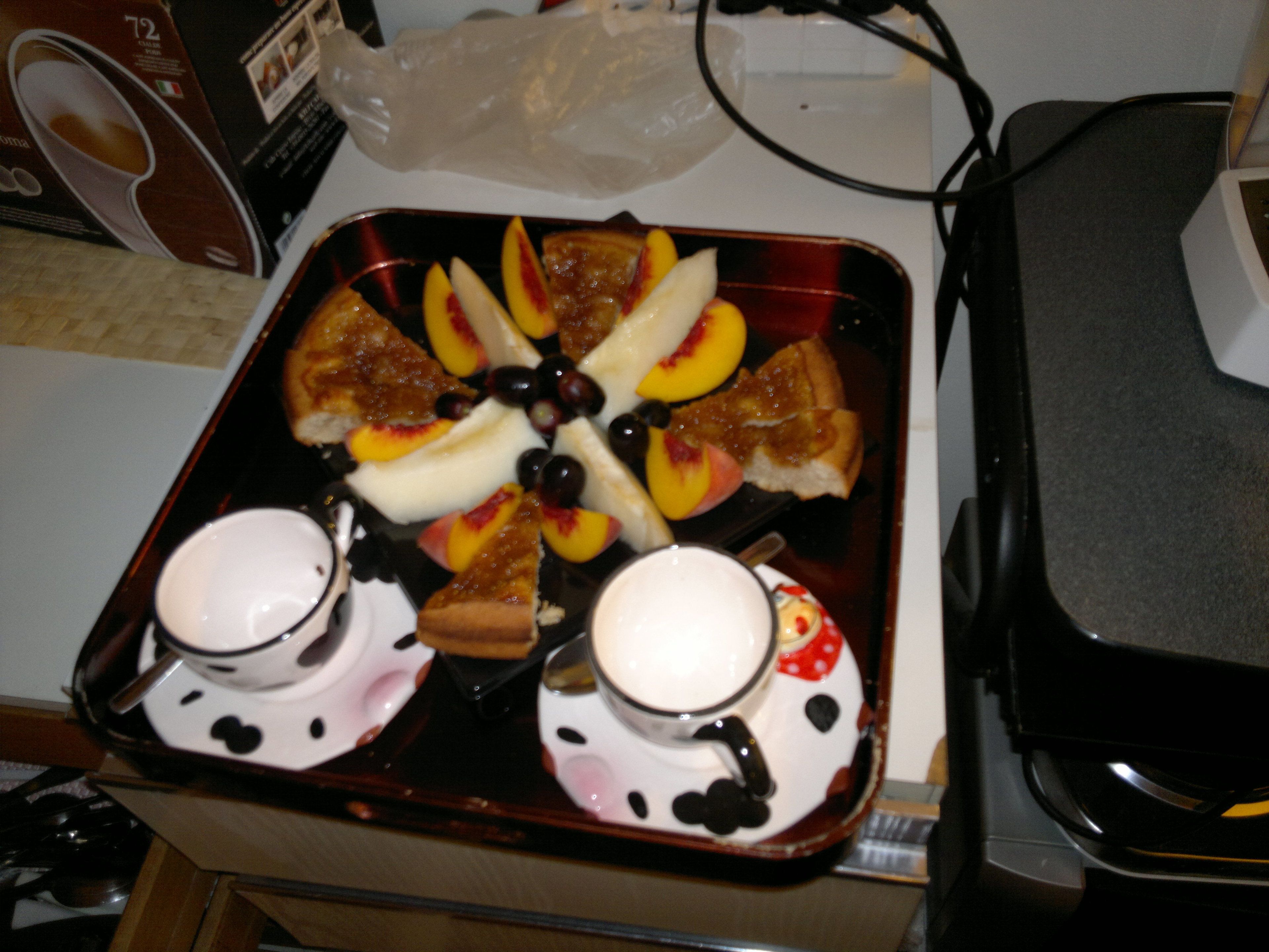 Una bandeja con comida y dos tazas sobre una mesa.