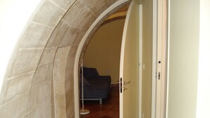 A room with a stone archway leading to a bedroom with a bed and a small round table. - Iblea Paradise (Ragusa)