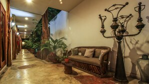 A hallway with a sofa, potted plants, and a candelabra. - Corazon de Jade Tulum Downtown (Tulum)