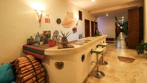 A bar area with a counter, stools, and a ceiling fan. - Corazon de Jade Tulum Downtown (Tulum)