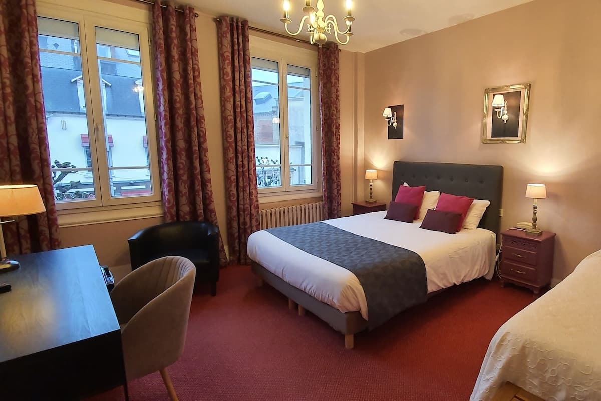 Ein Hotelzimmer mit zwei Betten, einem Schreibtisch, einem Stuhl und Blick ins Freie.