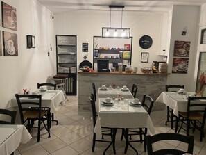 Ein Restaurant mit gedeckten Tischen, einer Kaffeestation und verschiedenen Wanddekorationen.