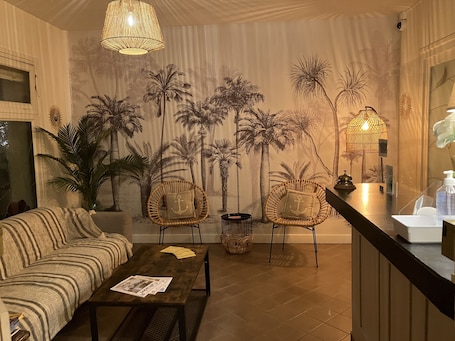 A cozy living room with a sofa, two wicker chairs, a coffee table, and a mural of palm trees.