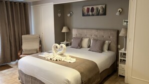 A hotel room with a large bed, a chair, a bedside table, a lamp, and a painting on the wall. - Hôtel de la Côte Fleurie (Deauville)