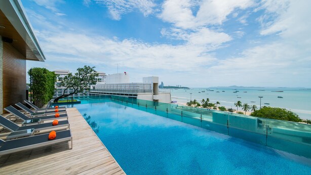 A poolside area with lounge chairs and a view of the beach and ocean.