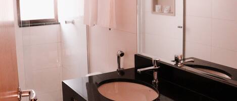 Une salle de bain moderne avec un lavabo noir, des toilettes blanches et un miroir.