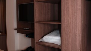 A room with a built-in wooden shelving unit, a flat-screen TV mounted on the wall, and a small desk with a telephone. - Vida Plaza Hotel (Nucleo Bandeirante)