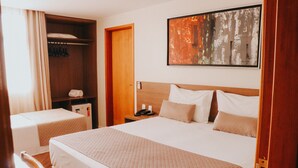 A hotel room with two beds, a wardrobe, a bedside table with a phone, and a painting on the wall. - Vida Plaza Hotel (Nucleo Bandeirante)