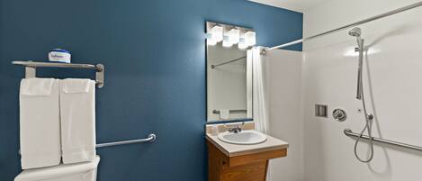 A bathroom with a blue wall, white sink, and a shower area.
