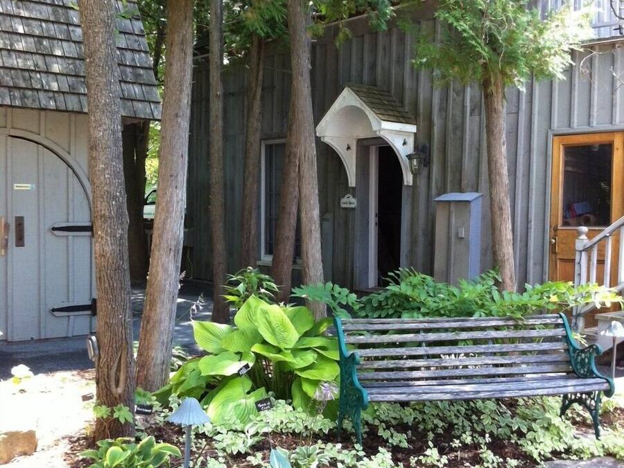 Een houten gebouw met een veranda, een bankje en diverse planten.
