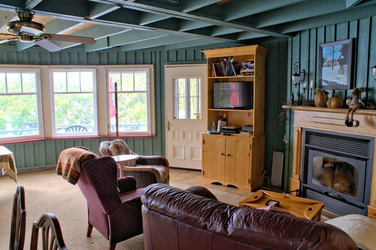 A cozy living room with a fireplace, wooden shelves, and a television.