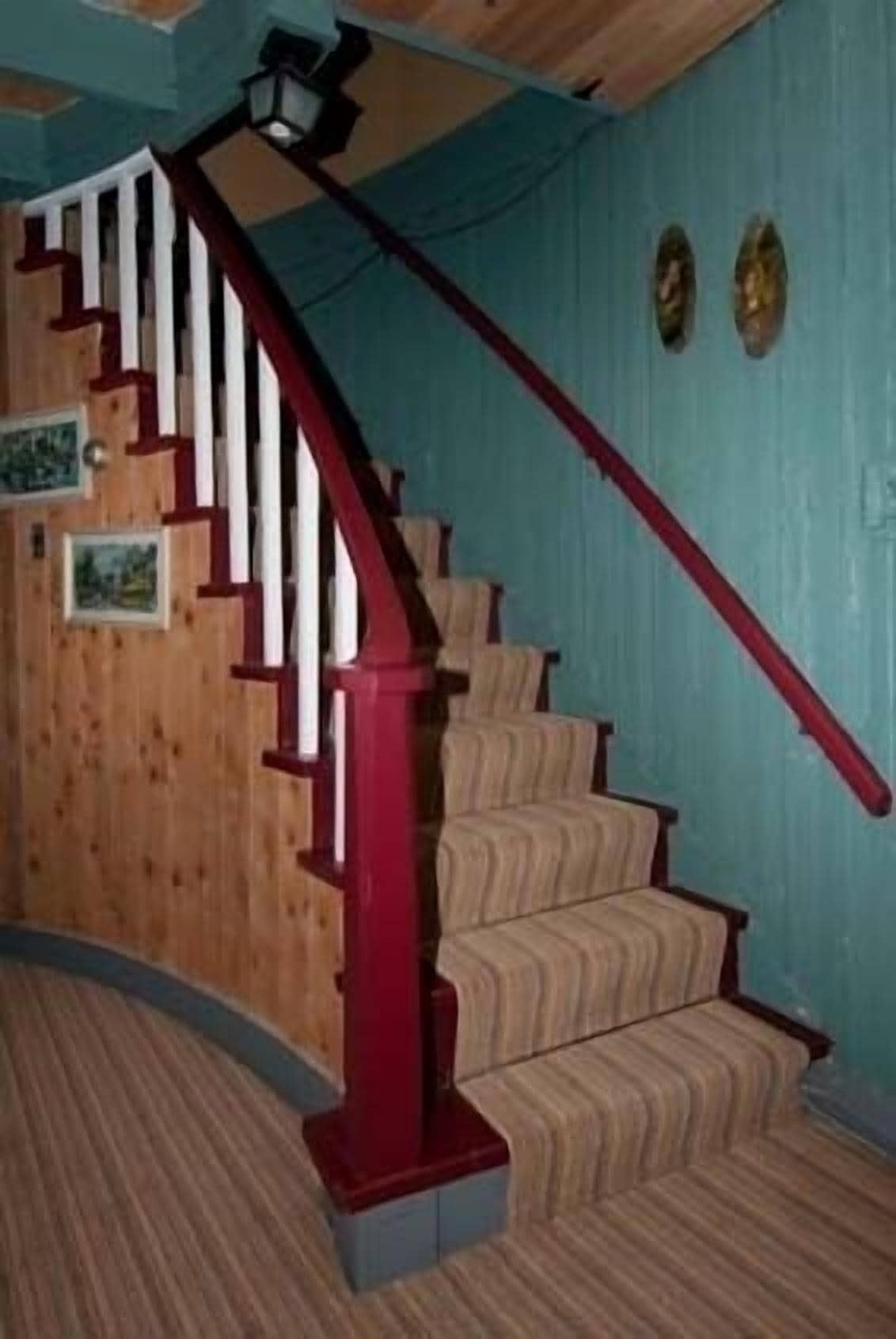 Una escalera de madera con barandillas rojas y peldaños color beige.