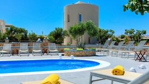 Un área de piscina con sillones de descanso y una pared de piedra.