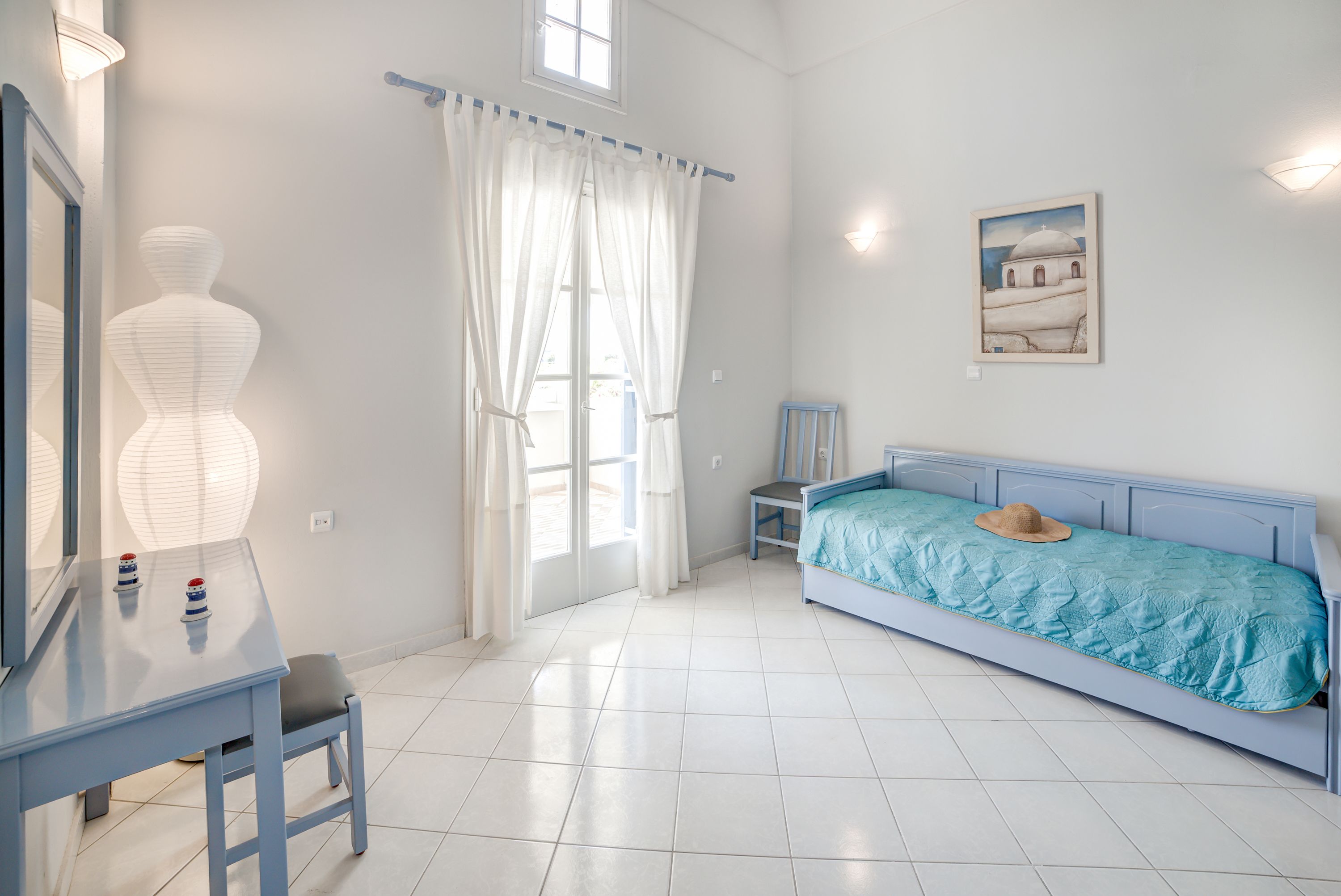 A bedroom with a bed, a desk, a chair, a mirror, and a window with curtains.