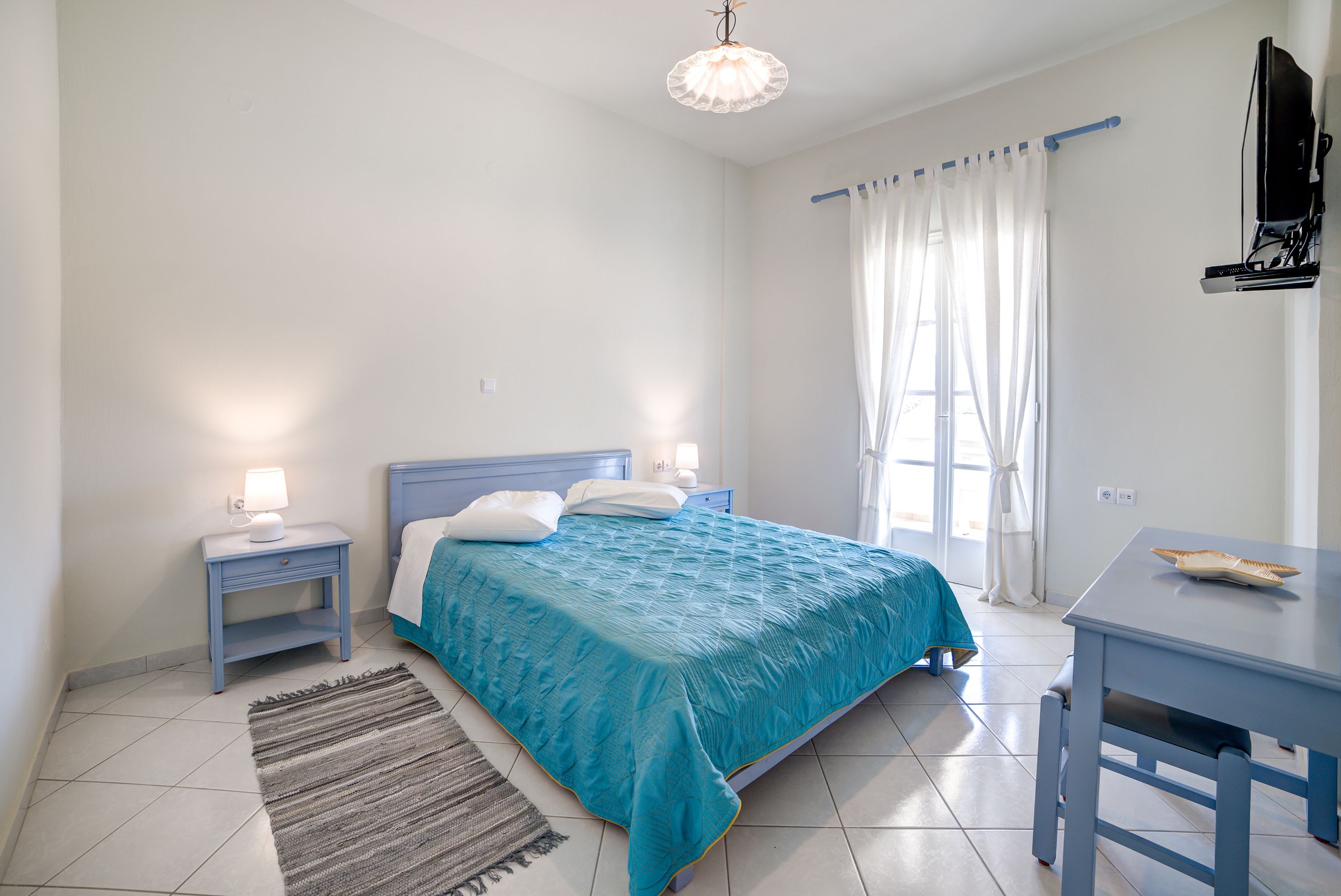 A bedroom with a bed, bedside tables, a desk, and a chair.
