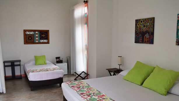 Habitación de hotel con dos camas, una mesita pequeña, una silla, un escritorio y una ventana con cortinas.