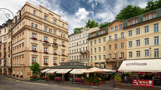 A hotel with multiple floors, outdoor seating, and flower boxes. - Hotel Ruze (Karlovy Vary)