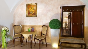 A dining area with a table and two chairs, a potted plant, a framed painting, and a wooden cabinet. - Hotel Ruze (Karlovy Vary)