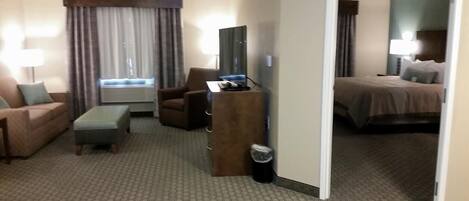 Habitación de hotel con sofá, sillón, escritorio y cama.