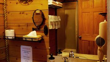 Baño de cabaña de madera con lavamanos, inodoro y espejo.