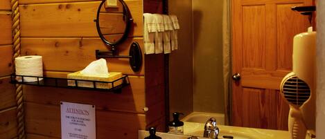 Une salle de bain rustique, aménagée dans une cabane en bois, avec un lavabo, des toilettes et un miroir.