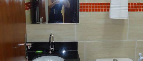 Une salle de bain avec un lavabo noir, un miroir, des toilettes blanches et un porte-serviettes.