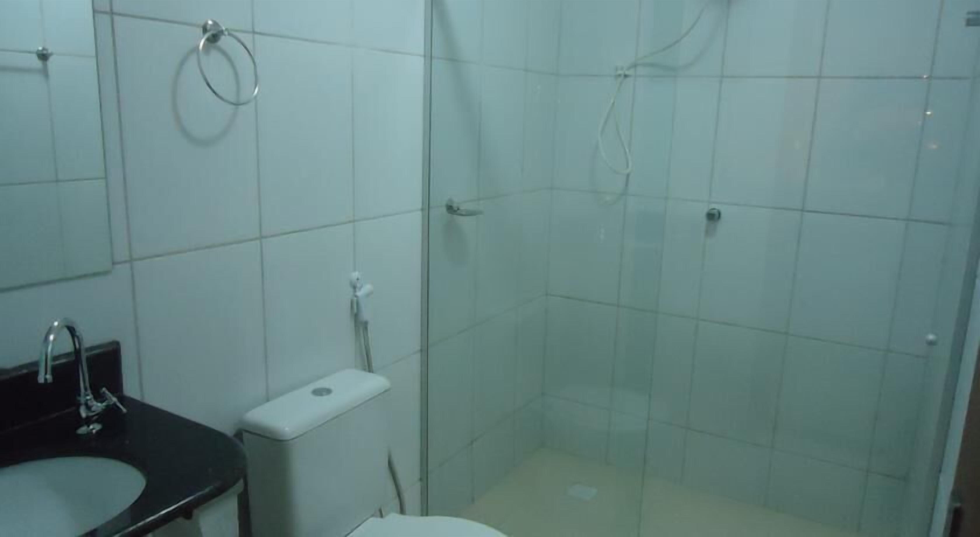 Un baño con lavamanos, inodoro y cabina de ducha con paredes de vidrio.