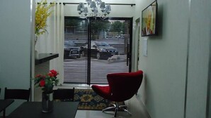 A dining area with a black table, red chair, and a vase of flowers. - Hotel MM (Nucleo Bandeirante)