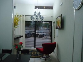 Uma área de refeições com uma mesa preta, uma cadeira vermelha e um vaso de flores.