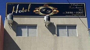 A building with a sign that reads "Hotel" and a phone number. There are two air conditioning units mounted on the building's facade. - Hotel MM (Nucleo Bandeirante)