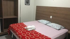 A bedroom with a bed, a wooden headboard, a wardrobe, and a framed picture on the wall. - Hotel MM (Nucleo Bandeirante)