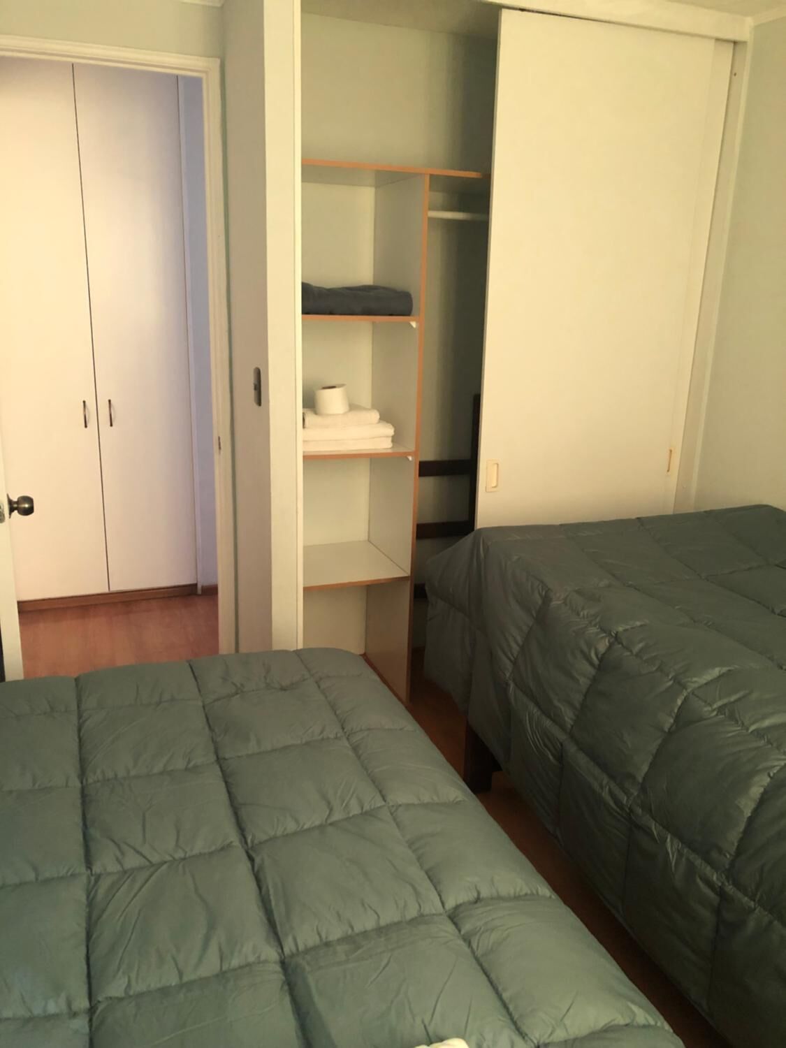 Un dormitorio con dos camas, un armario con estantes y una puerta.