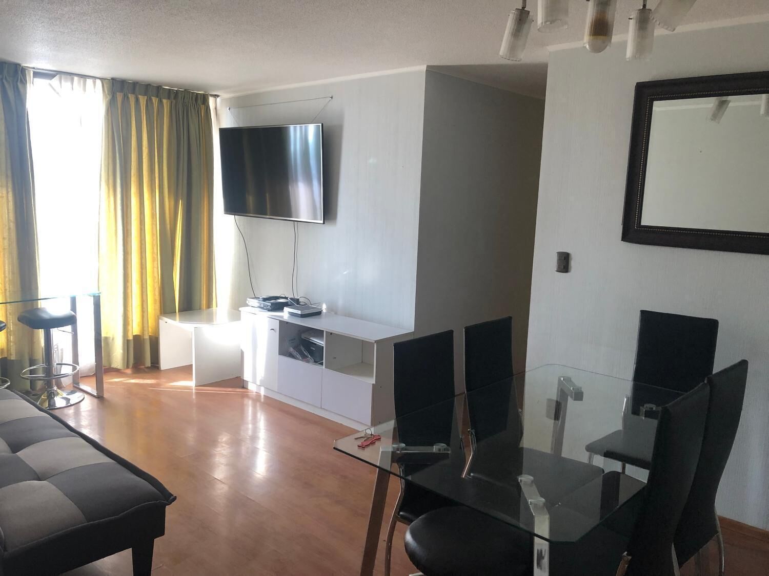 Una sala moderna con un televisor de pantalla plana, una mesa de comedor de vidrio y un sofá.