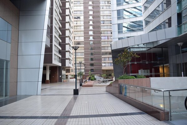 A modern urban building with a tiled plaza, glass railings, and a bike rack.