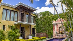 Une maison à deux étages dotée d’un balcon, d’une piscine et d’un jardin luxuriant.