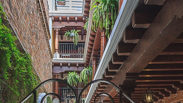 Une cour avec une grille en fer forgé, des murs en briques et des plantes en pot.