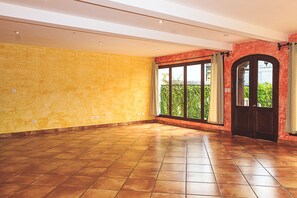 A spacious room with a large sliding glass door leading to a balcony with greenery.