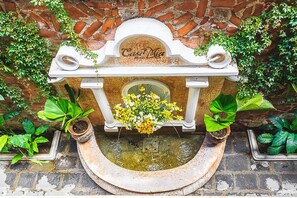 A fountain with a plaque reading "Casa Delia Hotel" surrounded by potted plants. - Casa Mia Hotel (Antigua Guatemala)