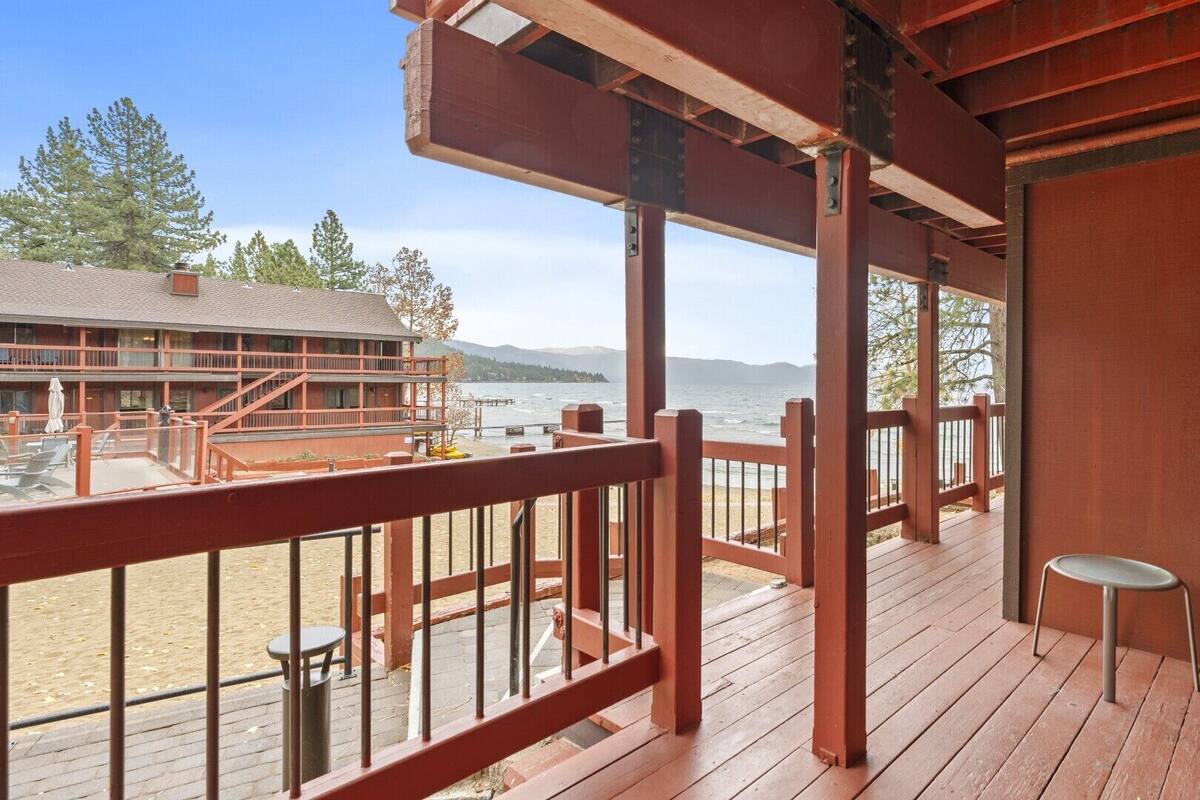 A wooden deck with a view of a lake and a building with multiple balconies.