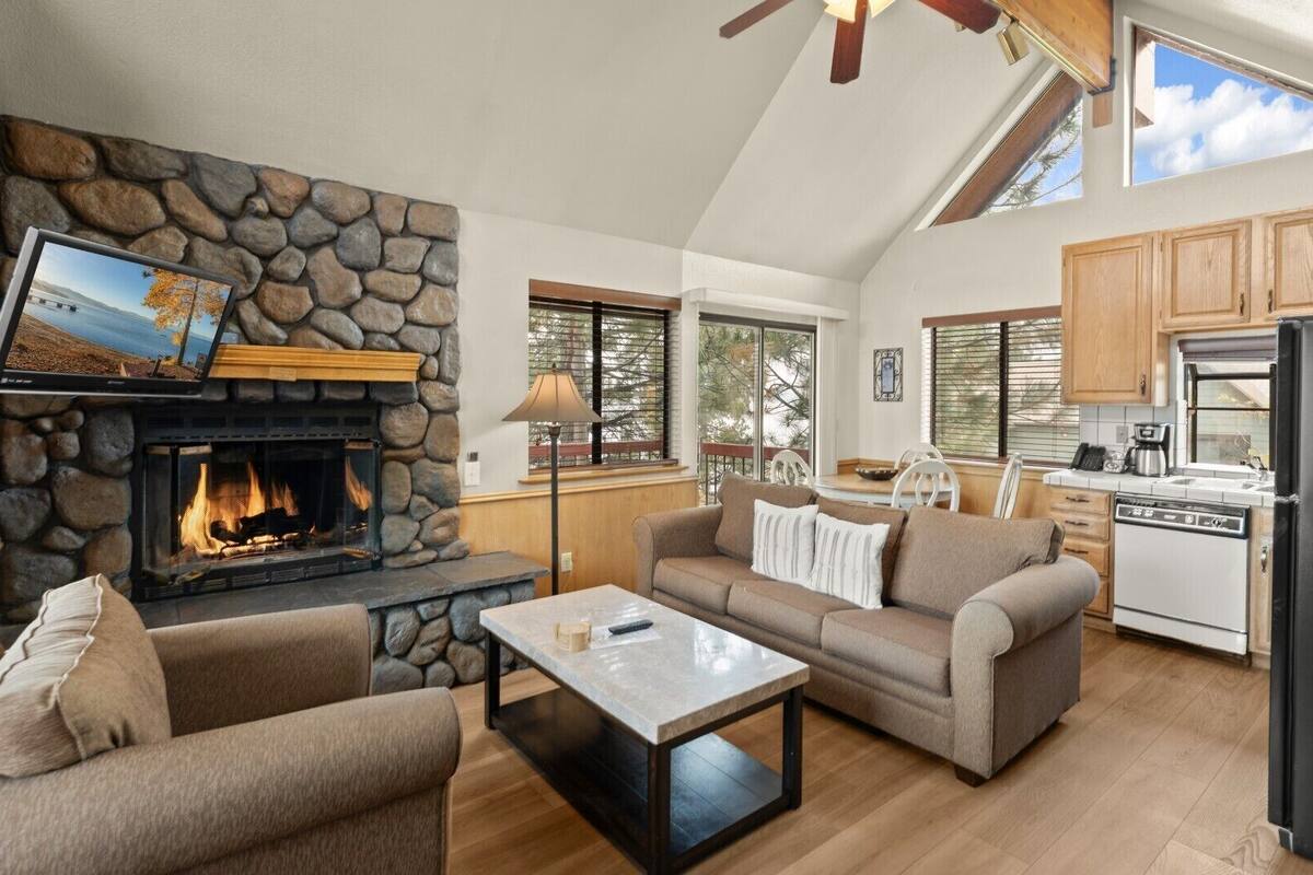 A cozy living room with a stone fireplace, a flat-screen TV, and a comfortable seating area.