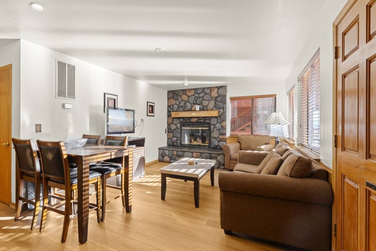 A spacious living room with a fireplace, a dining area with a table and chairs, and a cozy seating area with a sofa.