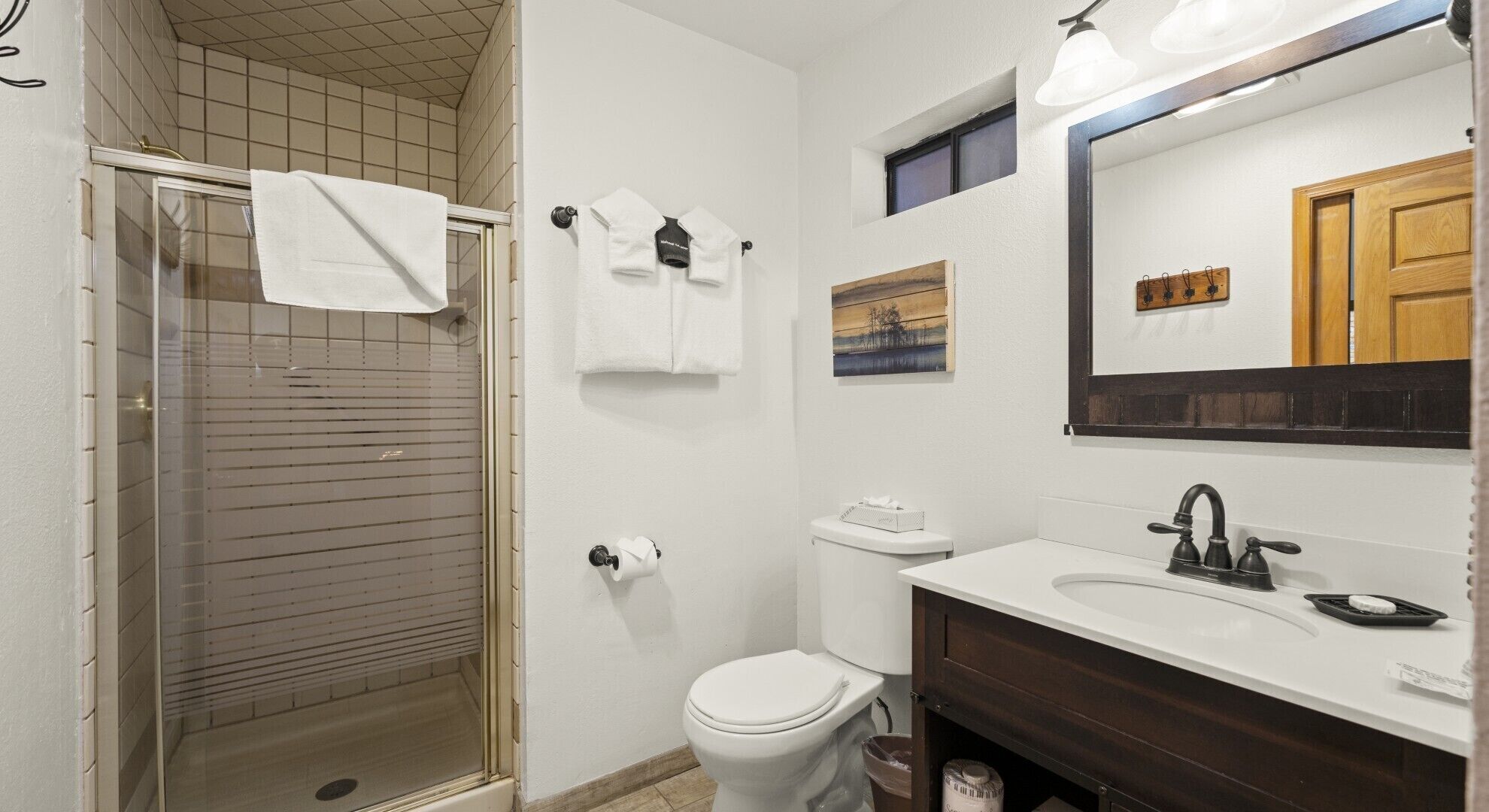 A bathroom with a shower, toilet, sink, and a mirror.