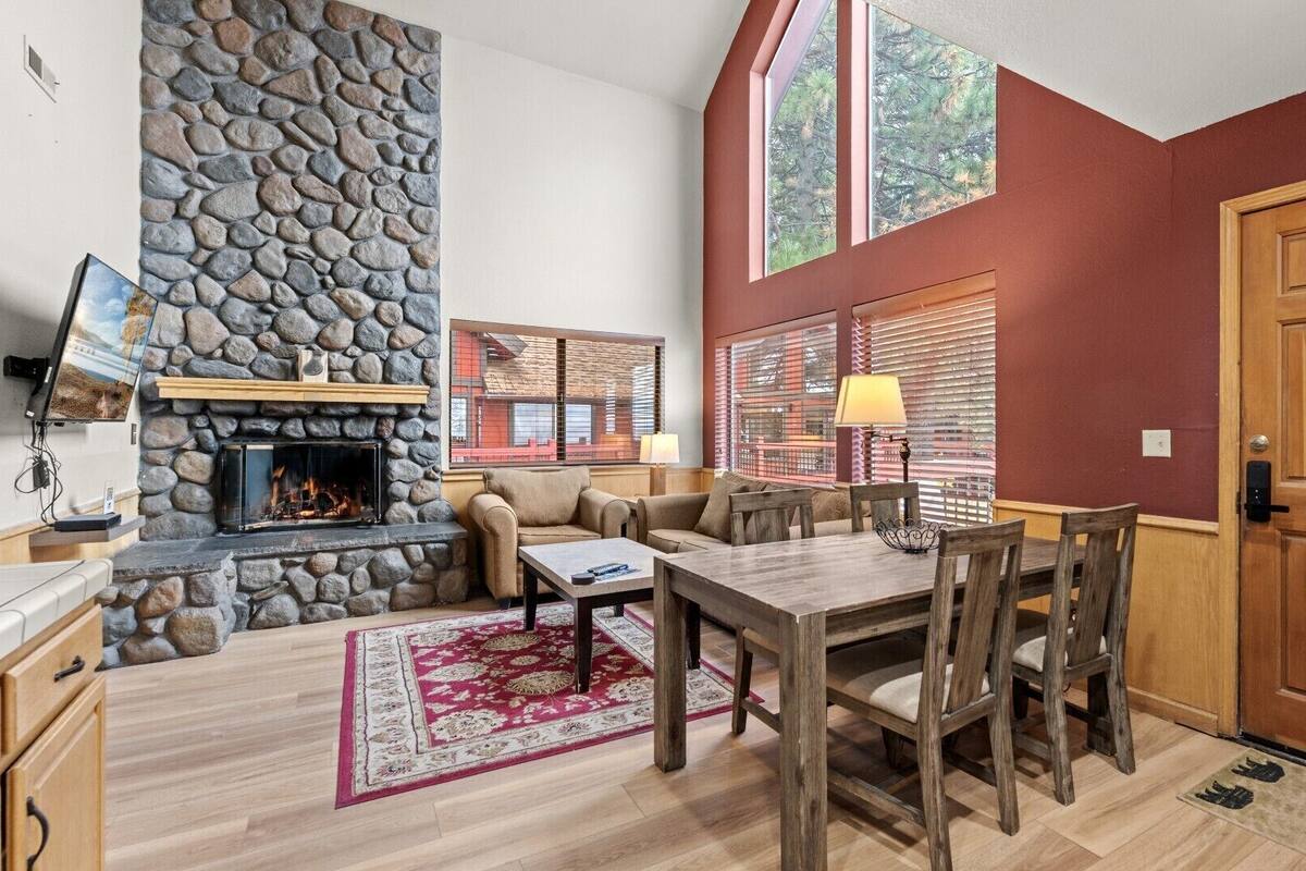 A cozy living room with a stone fireplace, wooden dining table, and comfortable seating.
