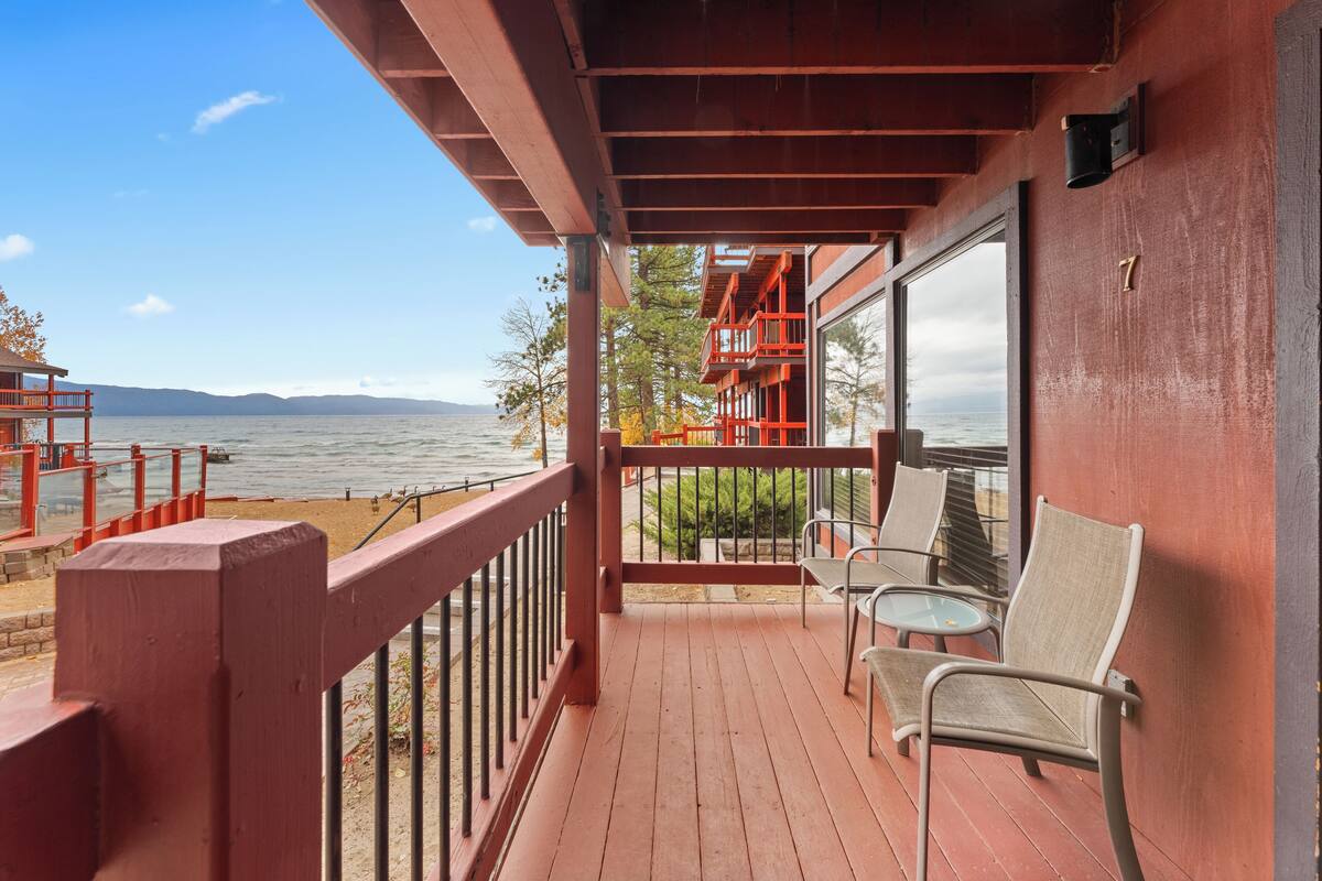 A wooden deck with chairs and a railing overlooking a body of water.