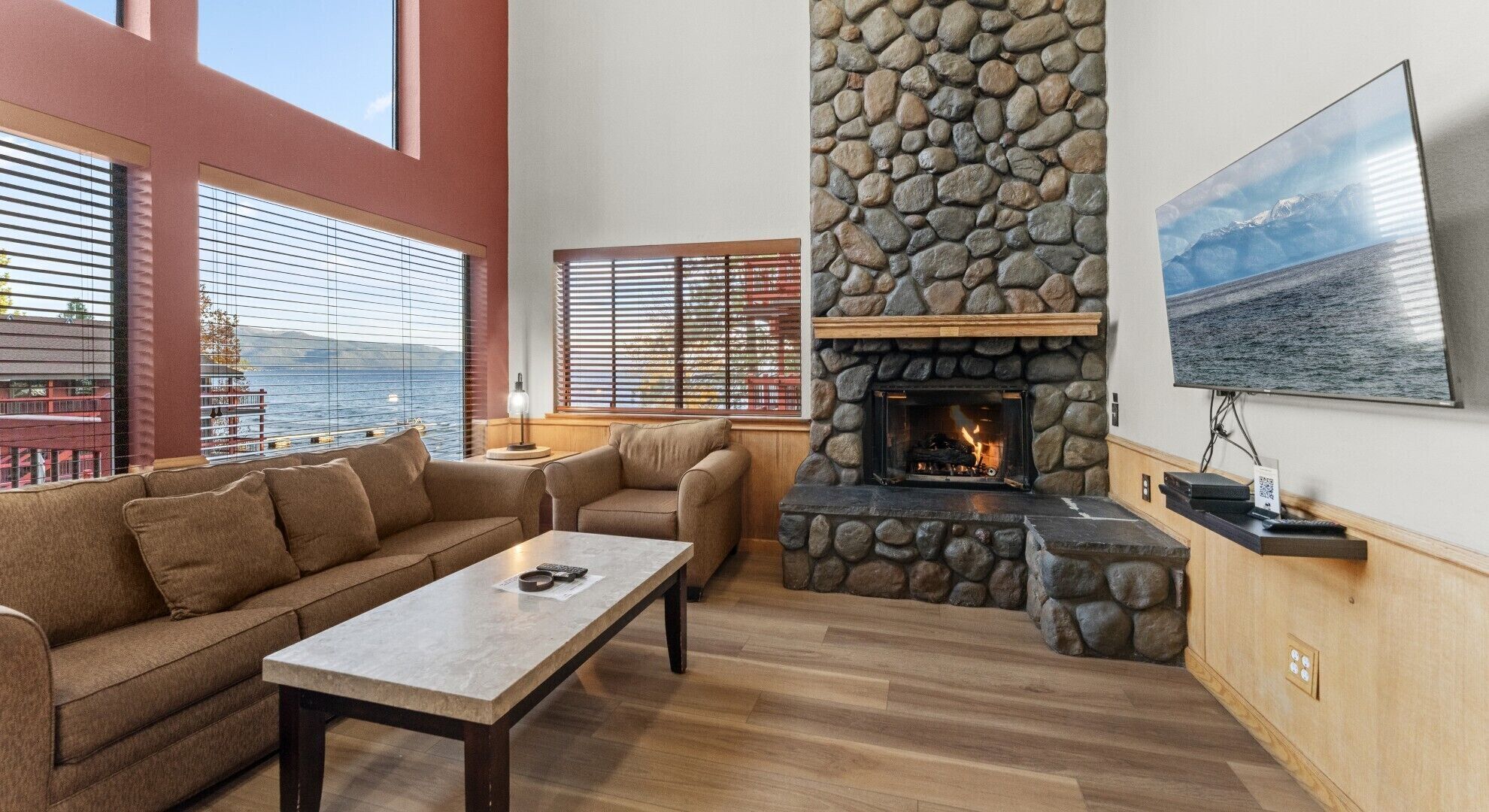 Ein gemütliches Wohnzimmer mit Kamin, Sofa, Couchtisch und Wand-Fernseher.