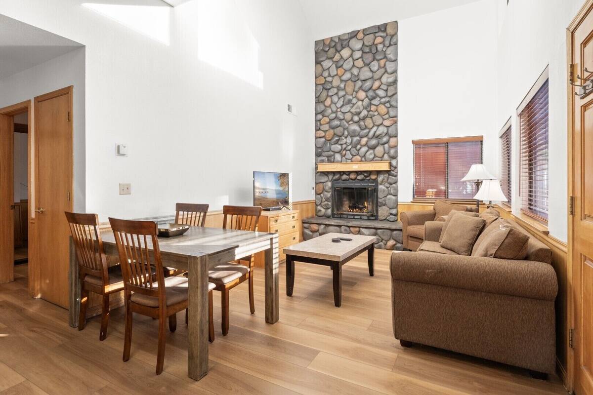 A spacious living room with a stone fireplace, wooden furniture, and a cozy seating area.