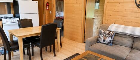 Un interior de cabaña acogedor con comedor, cocina y sala de estar.