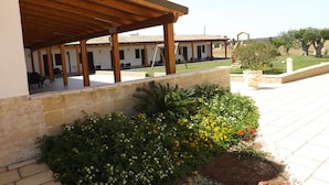 A covered outdoor area with stone walls and a garden with various flowers. - Il Mondo dei Sogni (Nardò)