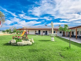 A hotel with a patio area, a children's play area, and a fountain.